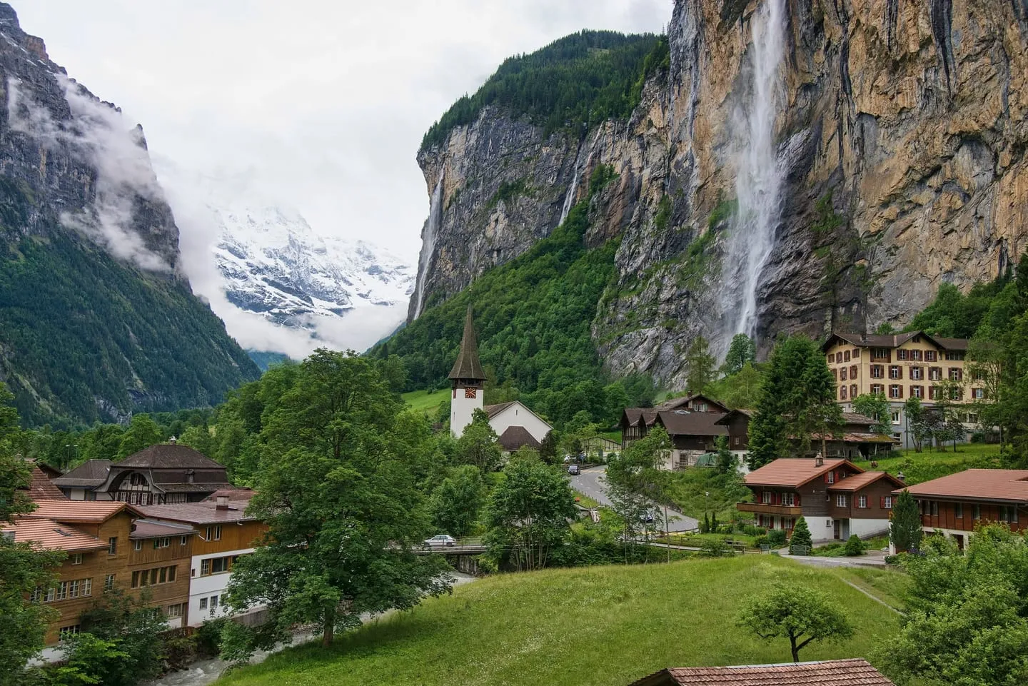 Lauterbrunnen village with its church and chalets below sheer cliffs and the Staubbach Falls dropping from the rim