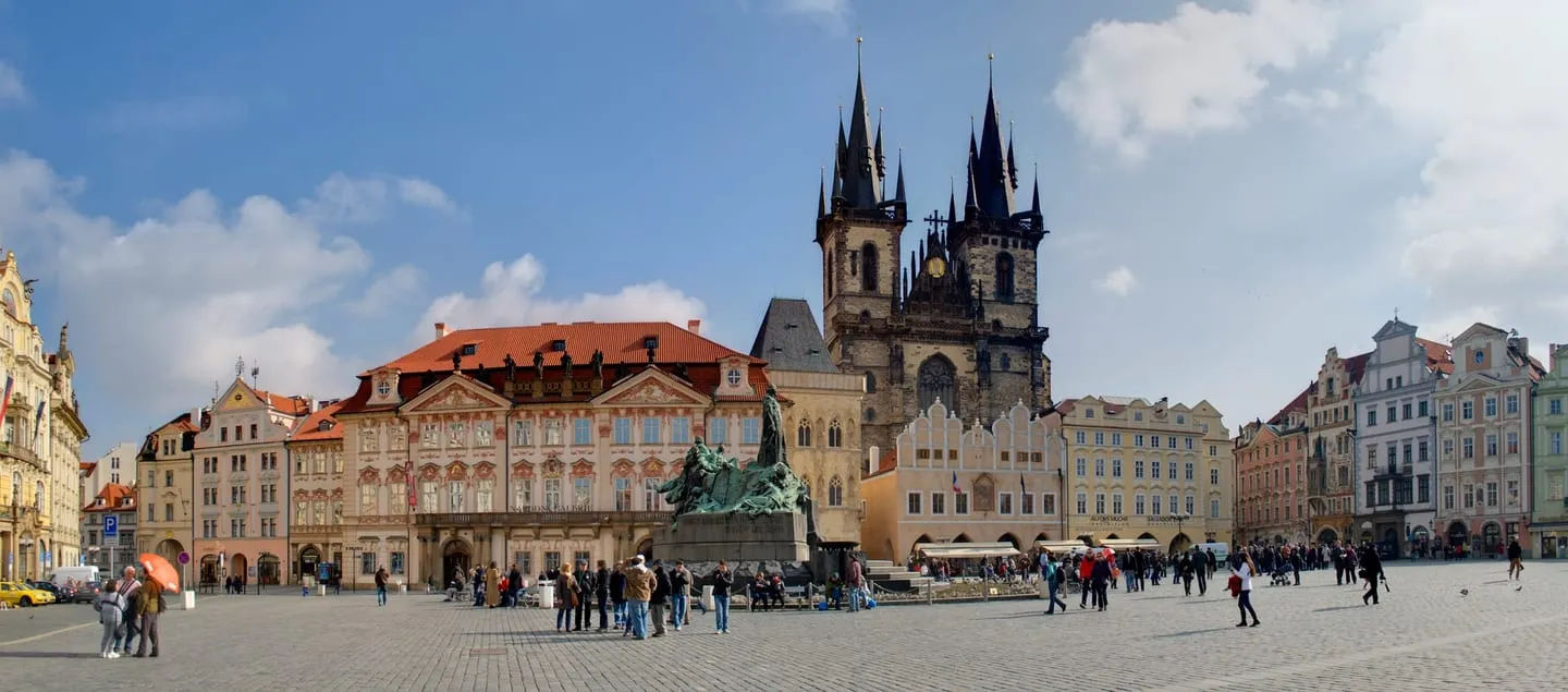 Old Town Square in Prague with the twin spires of the Týn Church behind a row of pastel baroque facades
