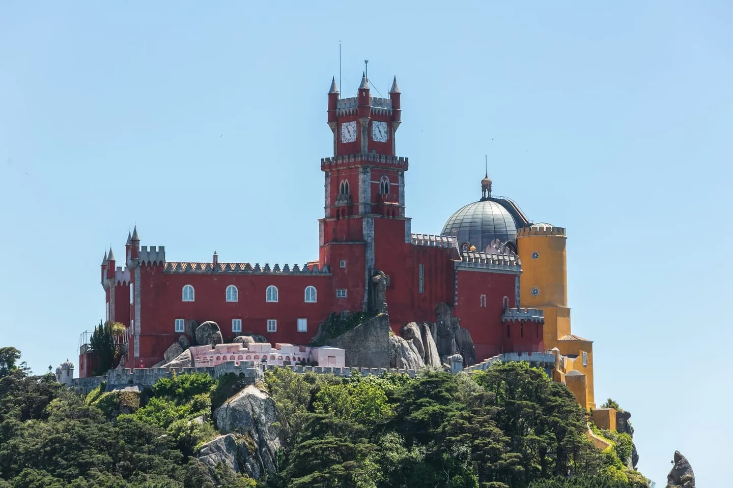 The red and yellow towers of Pena Palace rising above the wooded hilltop of the Sintra hills