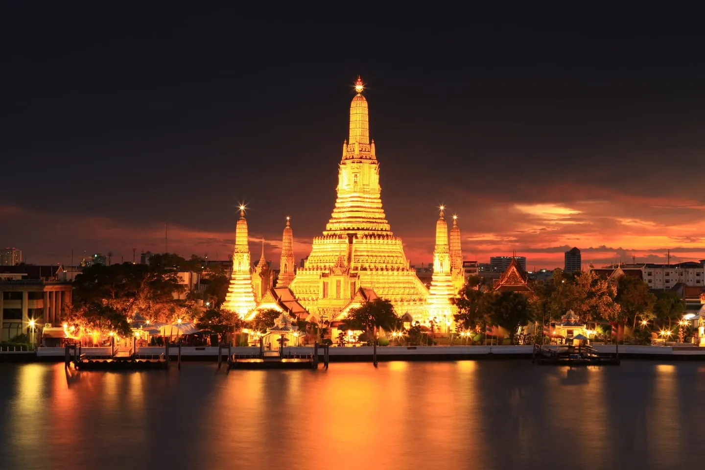 Wat Arun lit up at dusk on the far bank of the Chao Phraya River